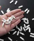 Hand holding white plastic pins from a 20 Pack Heavy Duty Shutter Repair Pins For Plantation Blinds.