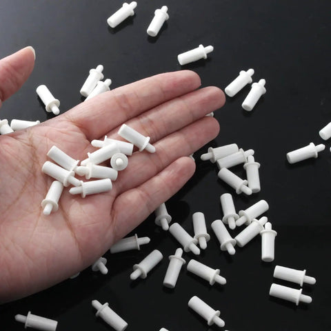 Hand holding white plastic pins from a 20 Pack Heavy Duty Shutter Repair Pins For Plantation Blinds.