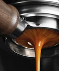 Close-up of Top Shelf 58mm Bottomless Portafilter with Smooth Walnut Grip for Breville, pouring fresh espresso.