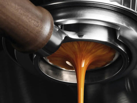Close-up of Top Shelf 58mm Bottomless Portafilter with Smooth Walnut Grip for Breville, pouring fresh espresso.