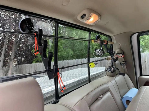 Rear car interior showing adjustable horizontal fishing rod rack with suction cup mount holding rods on rear window.