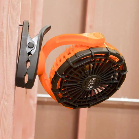 Cordless Rechargeable Fan With USB-C Charging Cord And Multiple Mounting Options For The Jobsite, clipped on wood surface