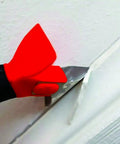 Close-up of Three In One Caulk Tool For Removal And Application With Soft Grip Handle showing stainless steel blade in use.