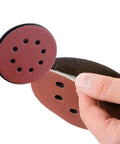50 Piece 5 Inch Sanding Discs with Eight Holes for Rock Solid Wood Metal Paint Smoothing, showing tactile hand grip on disc.