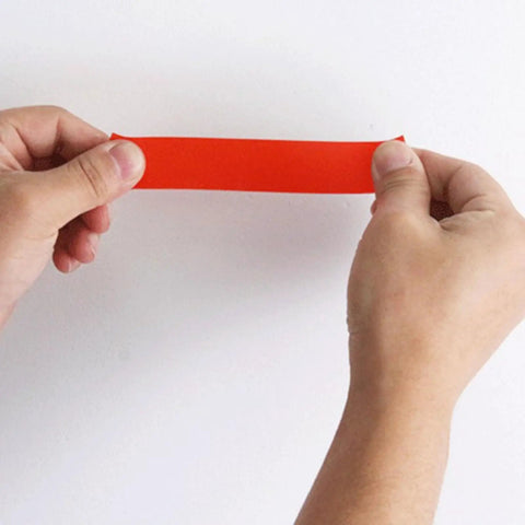 Top Notch Pipe Repair Tape That Seals Waterproof Leaks In A Flash held in hands showing red self-fusing adhesive tape.