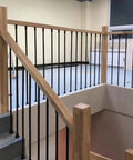Top Tier Adjustable Black Wrought Iron Stair Railing For Indoor And Outdoor Deck Projects, with wooden handrail and balusters.