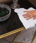 Hand using Pack Of 150 Cotton Shop Towels 12 By 14 Inches Absorbent Multipurpose Cleaning Rags For Auto Shops Garages And Home Use Durable 100 Percent Cotton Reusable For Spill Cleanup And Messes Machinery Wipe Down And Detail Work White on black table