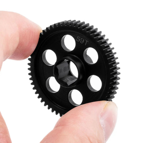 Hand holding Beefy Steel Main Gear 0.5M 59T RC Spur Gear for Arrma 1 By 18 Granite Grom Typhon upgrade, close-up view.