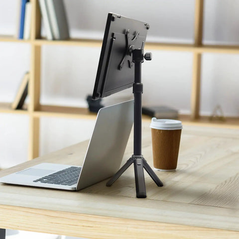 Metal Portable Monitor Stand Tripod With 360 Degree Ball Head Phone And Tablet Clamp on desk, next to laptop and coffee cup.