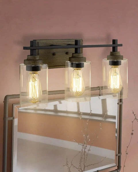 Farmhouse 3 Light Vanity Lighting Fixture in bronze and matte black with clear cylinder glass over mirror, 21 inch bar