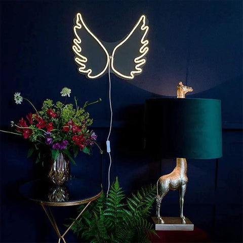 Cloud Neon LED Wall Light Sign USB Powered Night Lamp with angel wing shape on dark wall beside floral decorations.