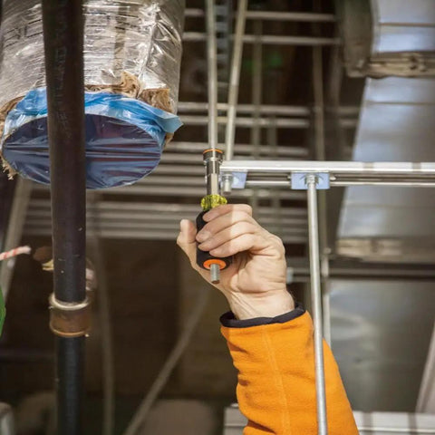 Person using Go-To Heavy-Duty Nut Driver With Hollow Shaft For Long Bolts, Nine Sixteenth Inch Tip, on overhead ductwork.