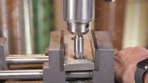 Close-up of a Three Piece Single Flute Countersink Set With 82 Degree Cutting Angle in use on metal in a drill press.