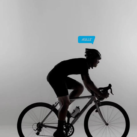 Cyclist on road bike silhouette with "AGILLE" speech bubble overhead, wearing helmet and cycling attire, gray background.