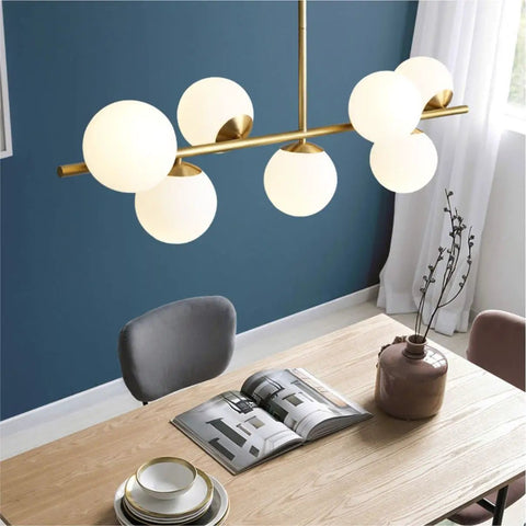 Groovy Mid Century Modern Pendant Light Set Featuring Sleek Glass Globes and Gold Finish Perfect for Kitchen Island or Dining Room with Seven Bulbs for a Rad Lighting Vibe and Dimmable LED Compatibility above a dining table.