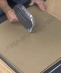 Person using LokDots Adhesive Dots Applicator for carpet tile installation on floor tiles, showing handheld design and application
