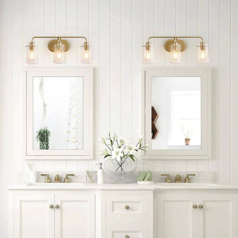 Bathroom with two white vanities and three light gold vanity light with seeded glass shades above mirrors.