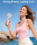 Woman using Portable Handheld Mini Fan With LED Display, 3-in-1 USB Rechargeable Fan And Flashlight For Travel by the sea
