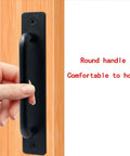 Close-up of Metal Barn Door Pull Set, Four Pack Long Base Flat Head Drawer Pulls, black finish, being held on wood door.
