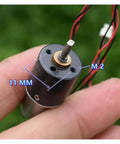 Close-up of 16mm 1215 Planetary Gearbox For DC Motors held in hand, showing 11mm measurements and wires, for DIY robotics projects.