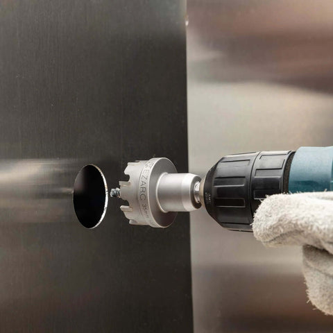 Close-up of EZARC 35mm carbide hole saw on a drill, cutting a metal panel with a pilot bit.