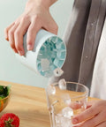 Person using 3D Upgraded Silicone Ice Cube Tray With Easy Release For Fast Ice 30 Cubes, Leak Proof And Space Saving Freezer Organizer, BPA Free, Ideal For Cocktails Coffee RV Office Parties Includes Travel Ice Bucket Blue to pour ice cubes into a glass
