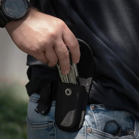Person placing 13 In 1 Stainless Steel EDC Multitool with Nylon Sheath for Camping, Hiking, and Fishing into a belt pouch outdoors.