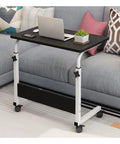 Multi Function Adjustable Height Laptop Desk Featuring Slick Rolling Casters And Sturdy Steel Build beside a couch with laptop and plant.
