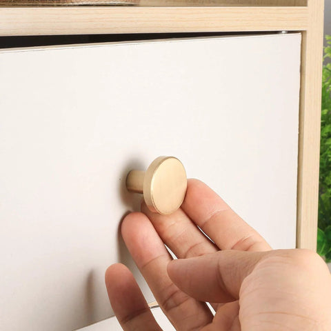 Hand installing Brushed Brass Cabinet Knobs Set Of 8 With Screws And Screwdriver 20X25 Mm Solid Brass Hardware on white drawer