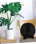 Heavy Duty Oxford Cloth Drum Gig Backpack With Rock Solid Adjustable Padded Straps And Hella Spacious Storage For Go Anywhere Drum Kit Gear And Cymbals resting on a chair beside a potted plant.