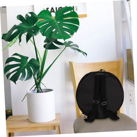 Heavy Duty Oxford Cloth Drum Gig Backpack With Rock Solid Adjustable Padded Straps And Hella Spacious Storage For Go Anywhere Drum Kit Gear And Cymbals resting on a chair beside a potted plant.