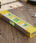 Spirit Level, Anodized Aluminum on wooden surface, featuring a yellow and black body, accurate bubble vials, and ruler.
