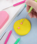 Person using Six Piece Cookie Scribe Tool Set Featuring Durable Iron Pins And Comfortable Plastic Handles For Flawless Sugar Cookie Decorating and Sweet Baker Crafts That Are Total Game Changers on yellow dough.