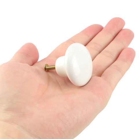 30 Pack White Ceramic Cabinet Knobs Glossy Mushroom Style drawer pull shown in hand with screw for size reference