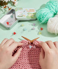 Flower Stitch Markers Set Of 18 In 9 Colors For Knitting Crochet And Weaving, shown with yarn and knitting in progress on a green table.