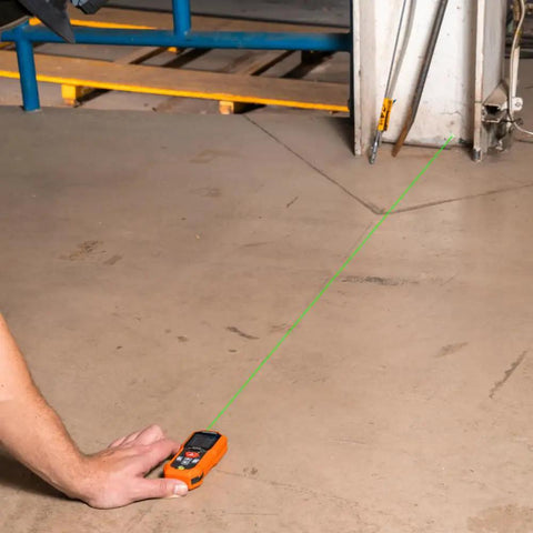 Green Laser Distance Measure Tool With 200 Foot Range For DIY And Pros in use on a concrete floor, showing green laser line.