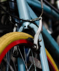 Close-up of bike frame with brake caliper and vibrant red and yellow tire, part of Six Pairs Bike Brake Pads With Hex Nuts And Spacers For Cruiser Mountain Bikes And MTB, Heavy Duty Rubber And Metal, Quieter Braking And Strong Stopping In All Weather, Front And Rear Left And Right Marked For Easy Install.