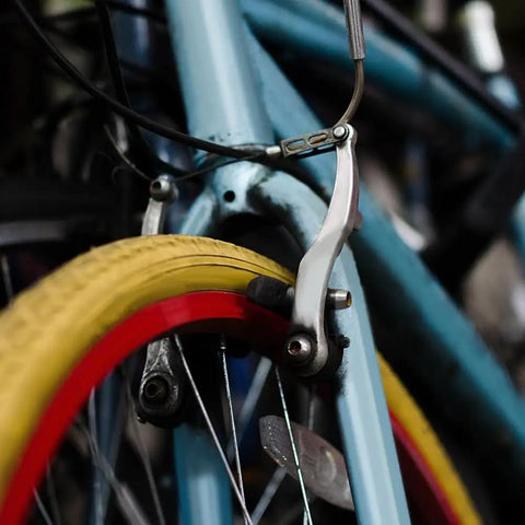 Close-up of bike frame with brake caliper and vibrant red and yellow tire, part of Six Pairs Bike Brake Pads With Hex Nuts And Spacers For Cruiser Mountain Bikes And MTB, Heavy Duty Rubber And Metal, Quieter Braking And Strong Stopping In All Weather, Front And Rear Left And Right Marked For Easy Install.