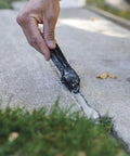 Applying Straightforward Concrete Crack Filler Gray Sealant for driveways onto a crack in a concrete slab.