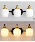 Bold Black And Gold 3 Light Vanity Light Fixture With White Glass Globe shown off and on against wall