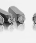Close-up of birth month flower metal stamping kit showing four 5/16 inch jewelry punch stamps with floral imprints.