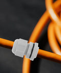 Close-up of a nylon adjustable cable gland on an orange cord for moisture-resistant sealing, part of the 25 Pack Nylon Adjustable Cable Glands Waterproof Cord Grips Heavy Duty Joint Connectors 3-15mm Range Built Tough For Any Electrical Setup Weather Resistant Seal Locks Wires Tight Never Let Moisture In Your Badass Wire Protection Gear.