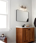 Avery 14.75 Inch Two-Light Vanity Light With Clear Seeded Glass In Olde Bronze over bathroom mirror and wooden vanity cabinet.