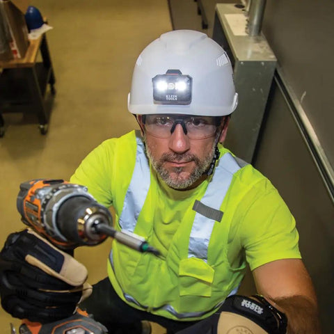Worker wearing vented safety helmet with rechargeable headlamp for at height and confined space work, lightweight hard hat with secure mounts.