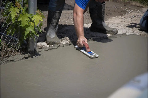 Man using White Lightning Hand Float For Concrete, 16 Inch Blade By 3 Inch, Smooths Bleed Water To The Surface on wet concrete