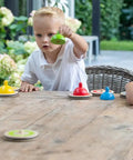 Children playing with Wooden Table Curling Set for Indoor Fun, 8 colorful stone pieces on a wooden table outdoors.