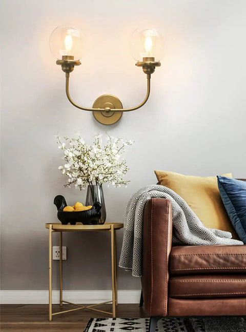Antique Brass Double Sconce Wall Light With Clear 5.9 Inch Globe Shade in a living room, E26 base, dimmable with compatible bulbs