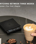 Ultra Slim Mini Coffee Scale With Timer For Espresso And Baking next to a cup of coffee on a black surface