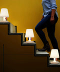 Tiny Rechargeable LED Lamp 2.0 Go Anywhere Dimmable Table Light on stairs with person walking, ideal for indoor outdoor use