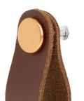 Close-up of leather furniture handle pull with screws for cabinets and doors brown leather cabinet knob hardware detail view